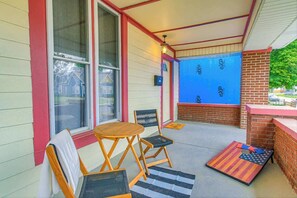 A covered patio area with a table and chairs, a small brick fireplace, and a blue wall with insulation. - Spacious and Fun 5BR w/ Pool Table and more! (Indianapolis)