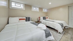 Una camera d'albergo con due letti, un'ampia finestra e una porta.