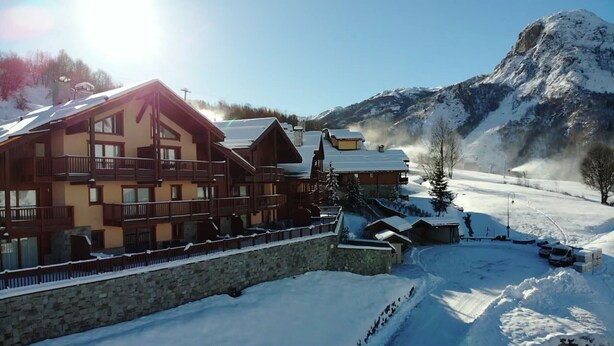 Ein Chalet-Hotel mit mehreren Balkonen und einer Steinwand.