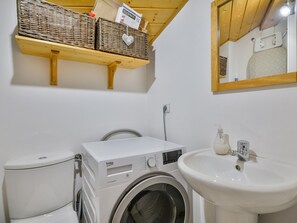 A compact bathroom with a washing machine, toilet, and sink.