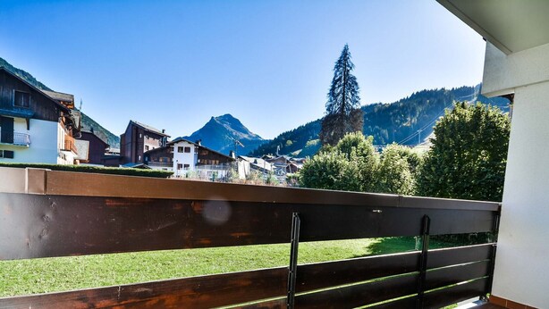 Ein Balkon mit Holzbalkon, der auf eine gebirgige Landschaft blickt.