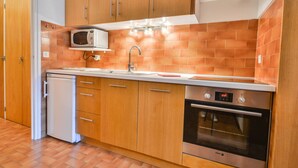 Eine kleine Küche mit Holzausstattung, einer Mikrowelle, einem Spülbecken, einem Geschirrspüler und einem Backofen.