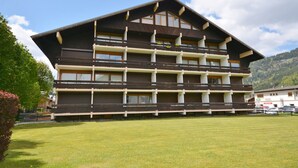 Ein mehrstöckiges Hotel im traditionellen alpinen Baustil, mit Balkonen und großen Fenstern.