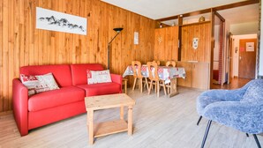 Ein gemütliches Zimmer mit einem roten Sofa, einem Holztisch und einem blauen Sessel.