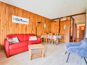 A cozy room with a red sofa, a wooden table, and a blue armchair.