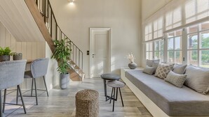 A spacious living area with a wooden staircase, a sofa set, and a dining table. - Leeda's Cottages (Zakynthos)