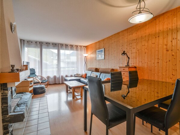 Una sala de estar acogedora con una pared de madera, un sofá, una mesa de centro y un comedor con sillas.