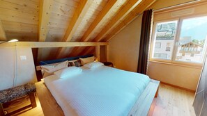 Ein gemütliches Schlafzimmer mit einem Bett, einem Nachttisch und einem Fenster mit Blick auf Gebäude.
