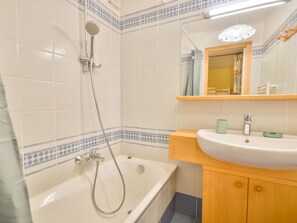 A bathroom with a bathtub, a shower, a sink, and a mirror.