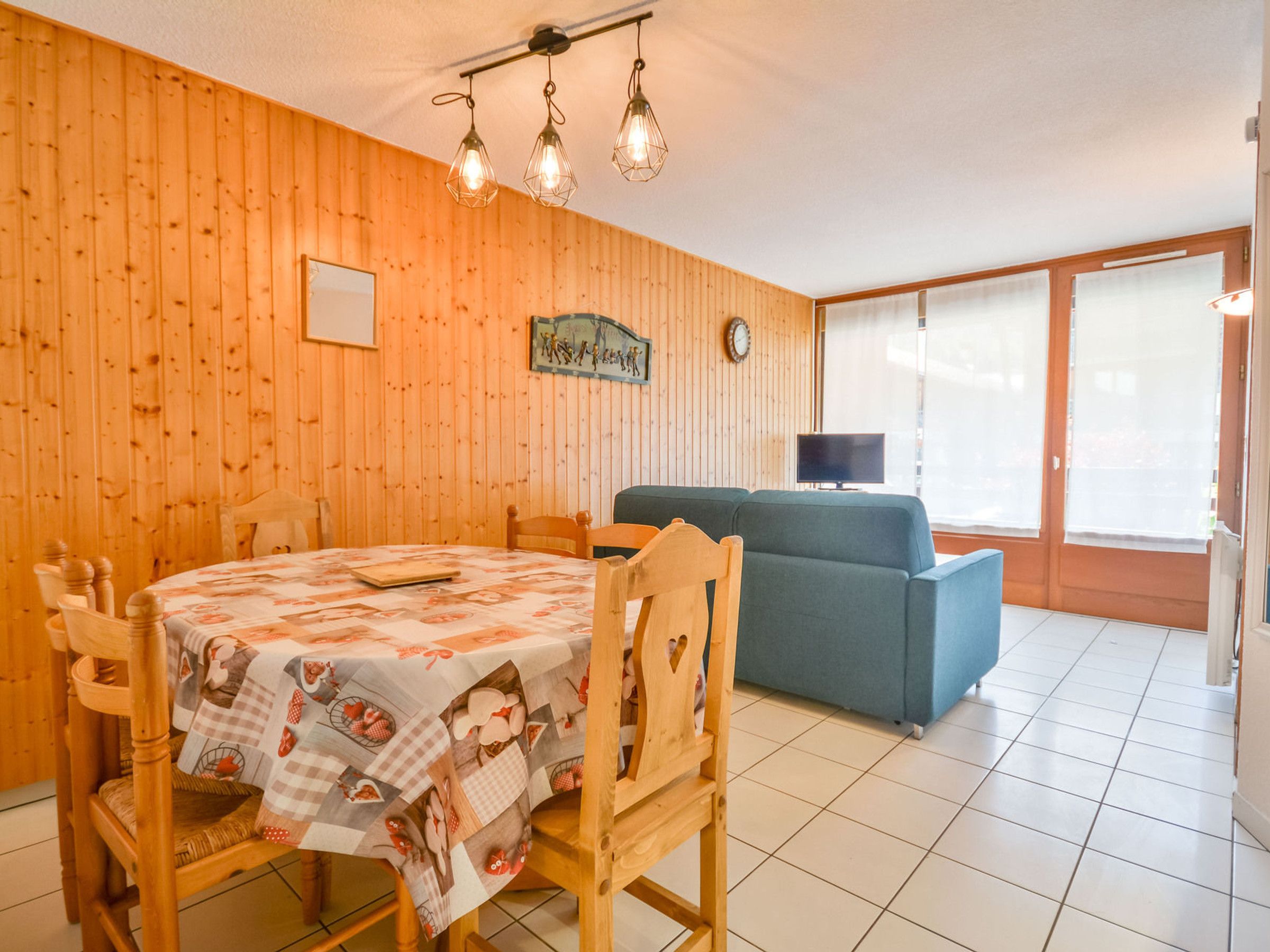 Un comedor con mesa de madera, sillas y sofá azul.
