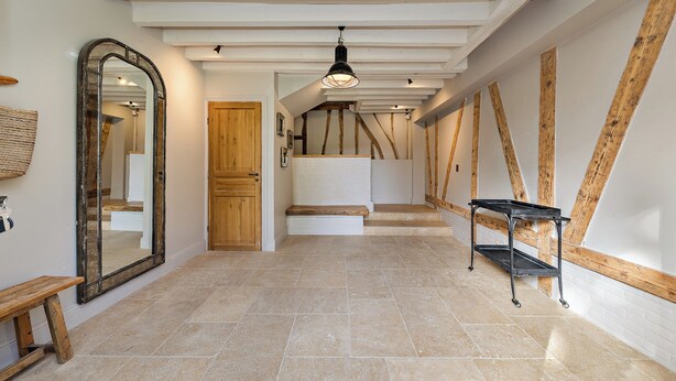 A hallway with a wooden bench, a large mirror, and a black metal table. - Magnificent house in Normandy (ROSAY SUR LIEURE)
