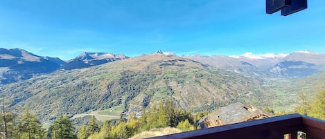 Vista de la montaña desde un balcón de madera con cielo despejado.