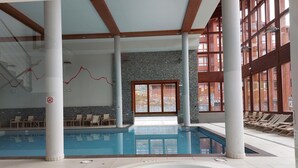 An indoor swimming pool with a hot tub, lounge chairs, and stone walls. - 3-room apartment with balcony, WIFI, parking and pool access, Les Arcs 1800 (Les Arcs 1800)