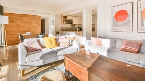 A modern living room with striped sofas, a wooden coffee table, and a kitchen in the background. - Stunning renovated T5, bright, sleeps 10 in Morzine (Morzine)