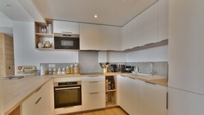 A modern kitchen with white cabinets, a microwave, oven, and a sink. - Stunning renovated T5, bright, sleeps 10 in Morzine (Morzine)