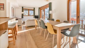 A modern living room with a dining area, large windows, and a view of a cityscape. - Stunning renovated T5, bright, sleeps 10 in Morzine (Morzine)