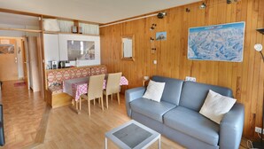 A cozy living room with a sofa, a coffee table, and a dining area with a table and chairs. - Studio in Morzine center, 4 pers, balcony, WIFI (Morzine)