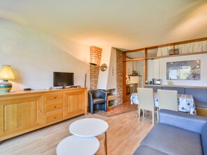 A living room with a sofa, a TV, a lamp, and a kitchen area in the background. - Studio in Morzine center, 4 pers, balcony, WIFI (Morzine)