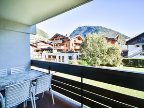 A balcony with a table and chairs, overlooking a mountain and traditional wooden buildings. - Studio in Morzine center, 4 pers, balcony, WIFI (Morzine)