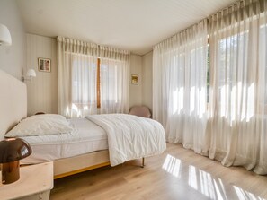 Une chambre à coucher avec un lit, une chaise, une lampe et des rideaux.