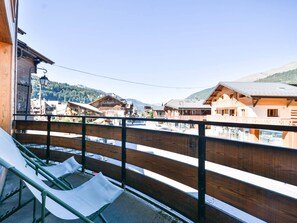 A balcony with a view of traditional wooden buildings and a mountain in the background.