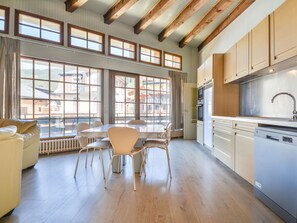 A spacious kitchen with wooden beams, large windows, and modern appliances.