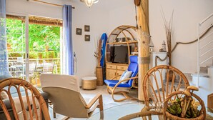 A living room with wicker furniture, a television, and a view of greenery outside. - 2 bedroom amazing home in Isla Cristina (Isla Cristina)