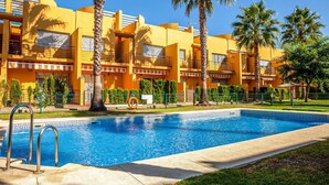 A hotel with a swimming pool, palm trees, and a yellow facade. - 2 bedroom amazing home in Isla Cristina (Isla Cristina)