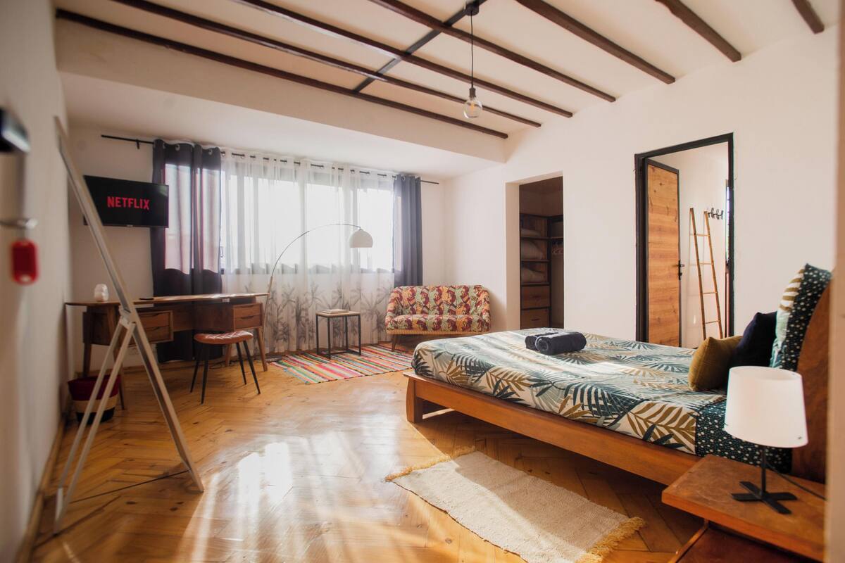 A bedroom with a bed, a desk, a chair, a TV, and a wardrobe.