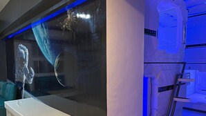 Une pièce moderne avec un grand aquarium, un banc et un mur au design futuriste agrémenté d’une échelle.
