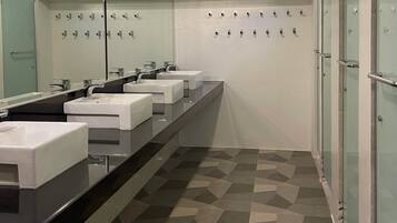 A modern bathroom with three sinks, a large mirror, and a patterned floor.
