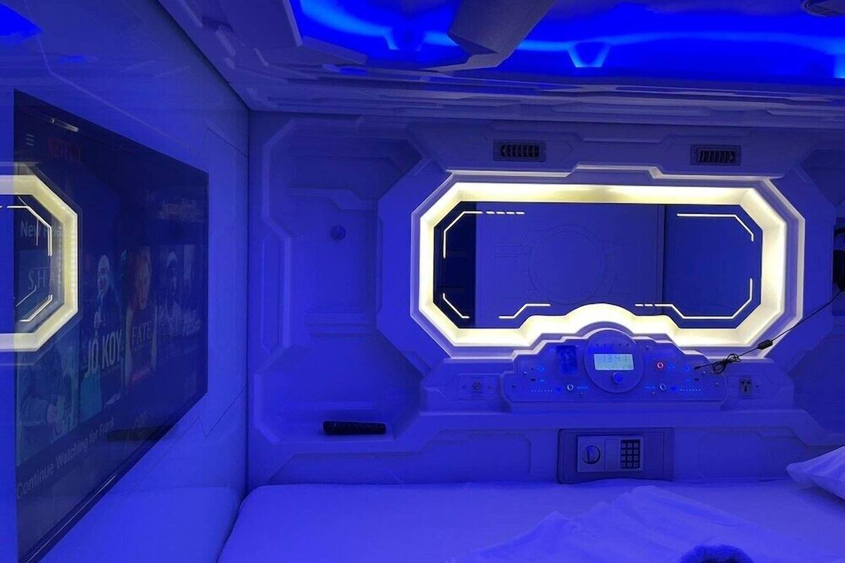A futuristic room with a central control panel, a large digital display, and a seating area.
