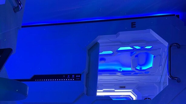 Une pièce futuriste dotée d’un panneau de contrôle central et d’une échelle menant à une plateforme.