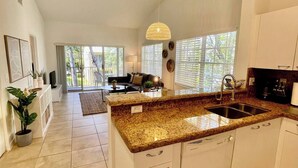 A spacious kitchen with a granite countertop, white cabinetry, and a large window providing natural light. - 260D - Boca Retreat w/ Pool, Parking, Near Evert Tennis & Shops (Boca Raton)
