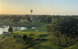 A golf course with a water tower, a pond, and a small building. - Grand Lake Getaway – Vista Towers 10th Floor Condo with Golf & Lake Views (Monkey Island)
