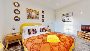 A modern bedroom with a yellow bed, a TV, and artwork on the walls. - Funky 2 Bed Apartment in the Heart of Historic Rochester (Rochester)