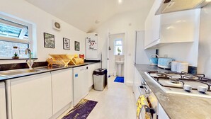 A modern kitchen with a built-in stove, a sink, and a window. There are framed pictures on the wall and a small trash bin. - Funky 2 Bed Apartment in the Heart of Historic Rochester (Rochester)