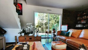 A modern living room with a sofa, ottoman, and a person relaxing on a wooden table. - Modern villa, ideal for families, at the gateway to the VERDON! (83111 - AMPUS)