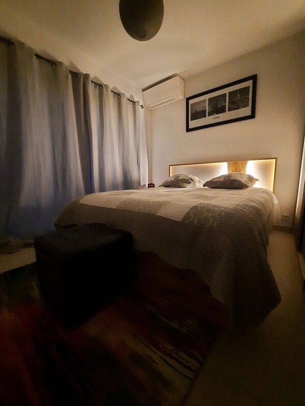 A bedroom with a bed, a bedside table, a chair, and a wall-mounted air conditioner. - Modern villa, ideal for families, at the gateway to the VERDON! (83111 - AMPUS)
