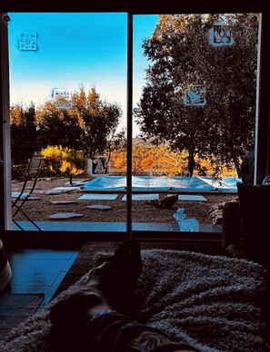 A room with a large window overlooking a backyard with a trampoline, a tree, and a chair. - Modern villa, ideal for families, at the gateway to the VERDON! (83111 - AMPUS)