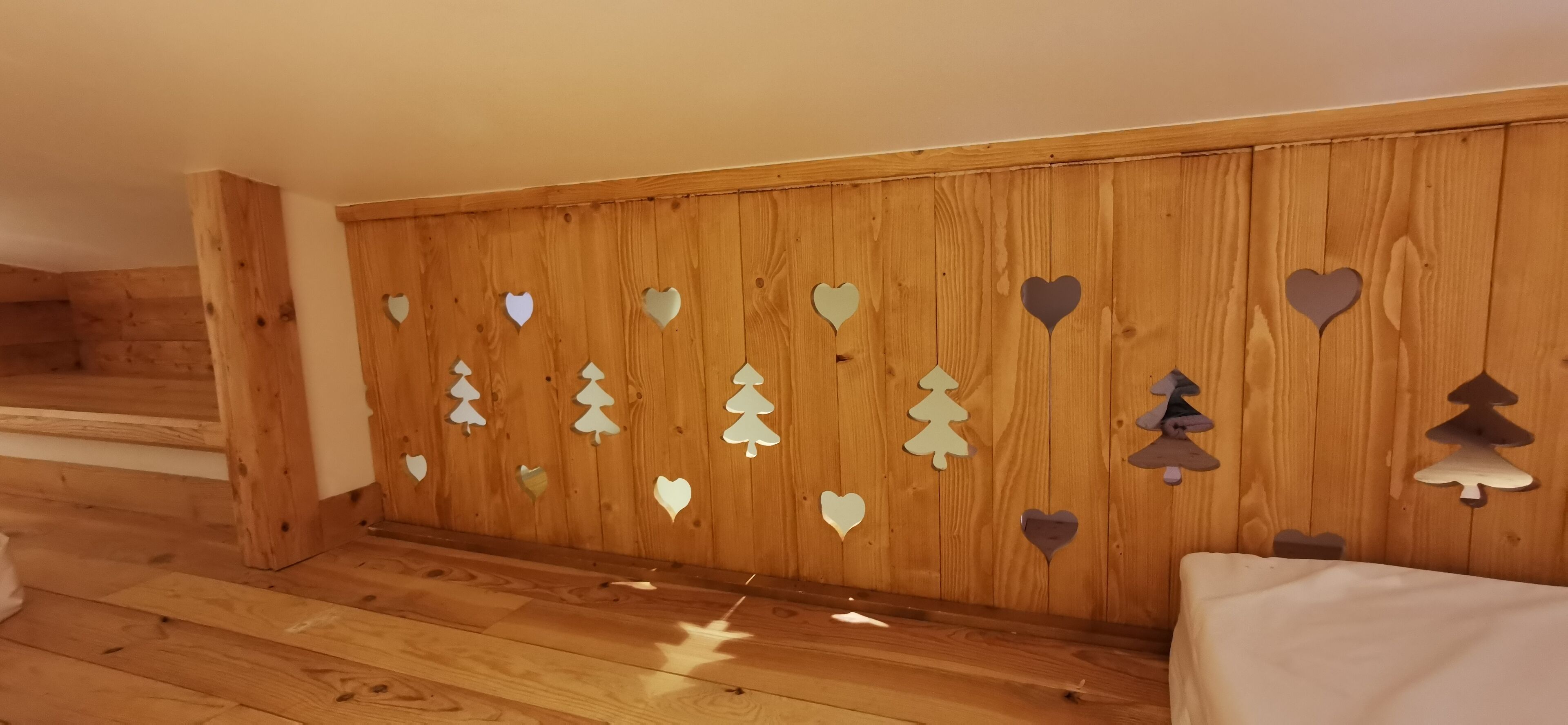 Een kamer met houten lambrisering, een bed en een trap.