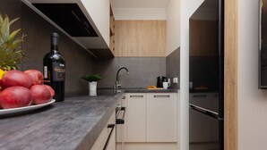 Una cocina moderna con encimera negra, armarios blancos, pileta de acero inoxidable y refrigerador negro.