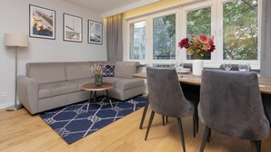 Una sala de estar moderna con un sofá, dos sillones, una mesita y un ventanal con vistas a árboles.