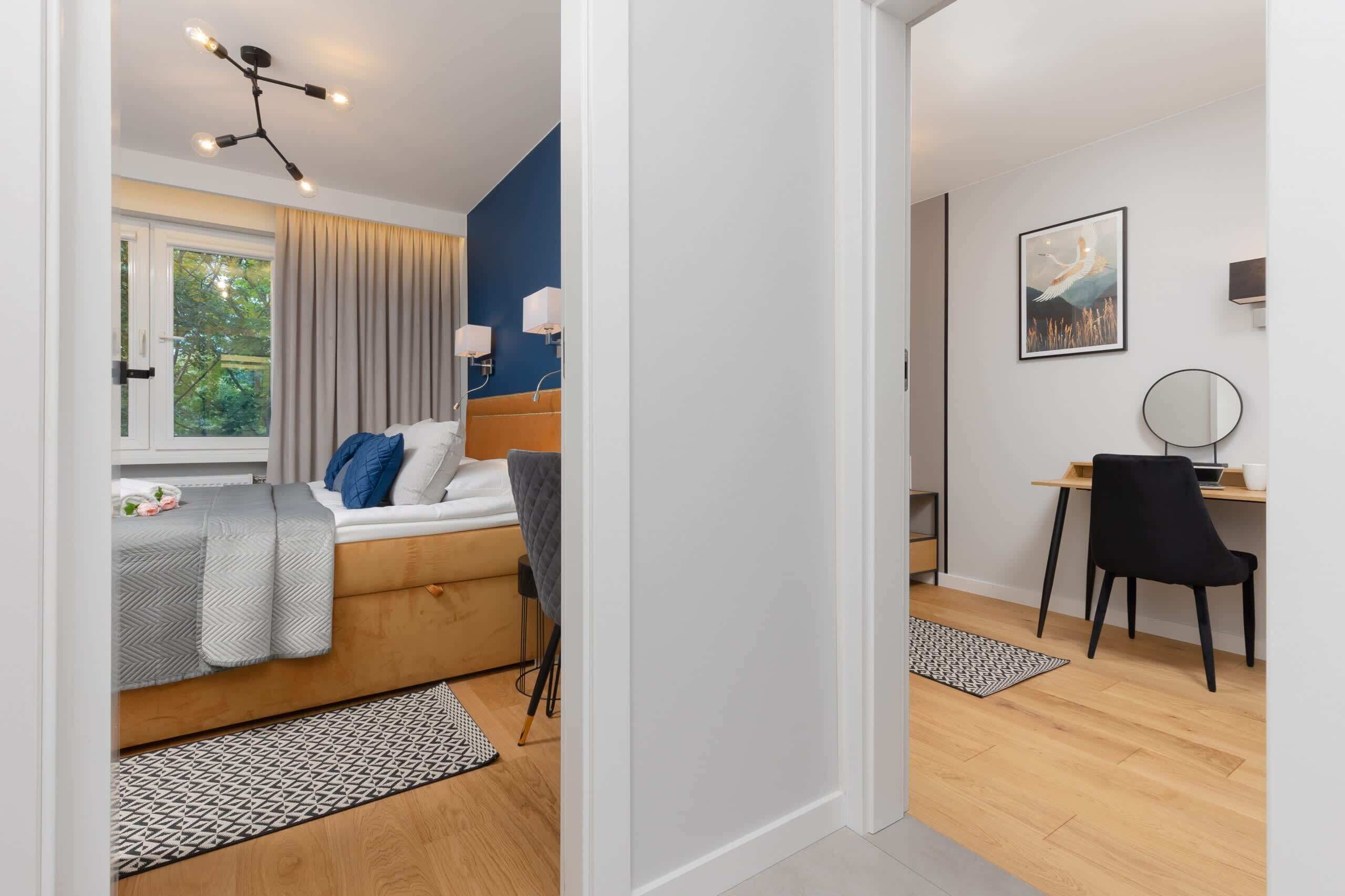 Un dormitorio moderno con cama, mesita de noche y escritorio con silla.