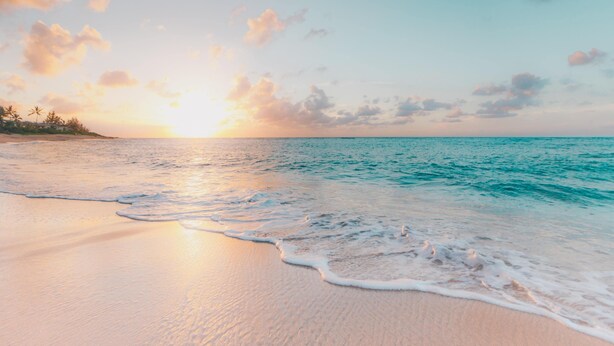 Una playa con olas suaves y un atardecer.