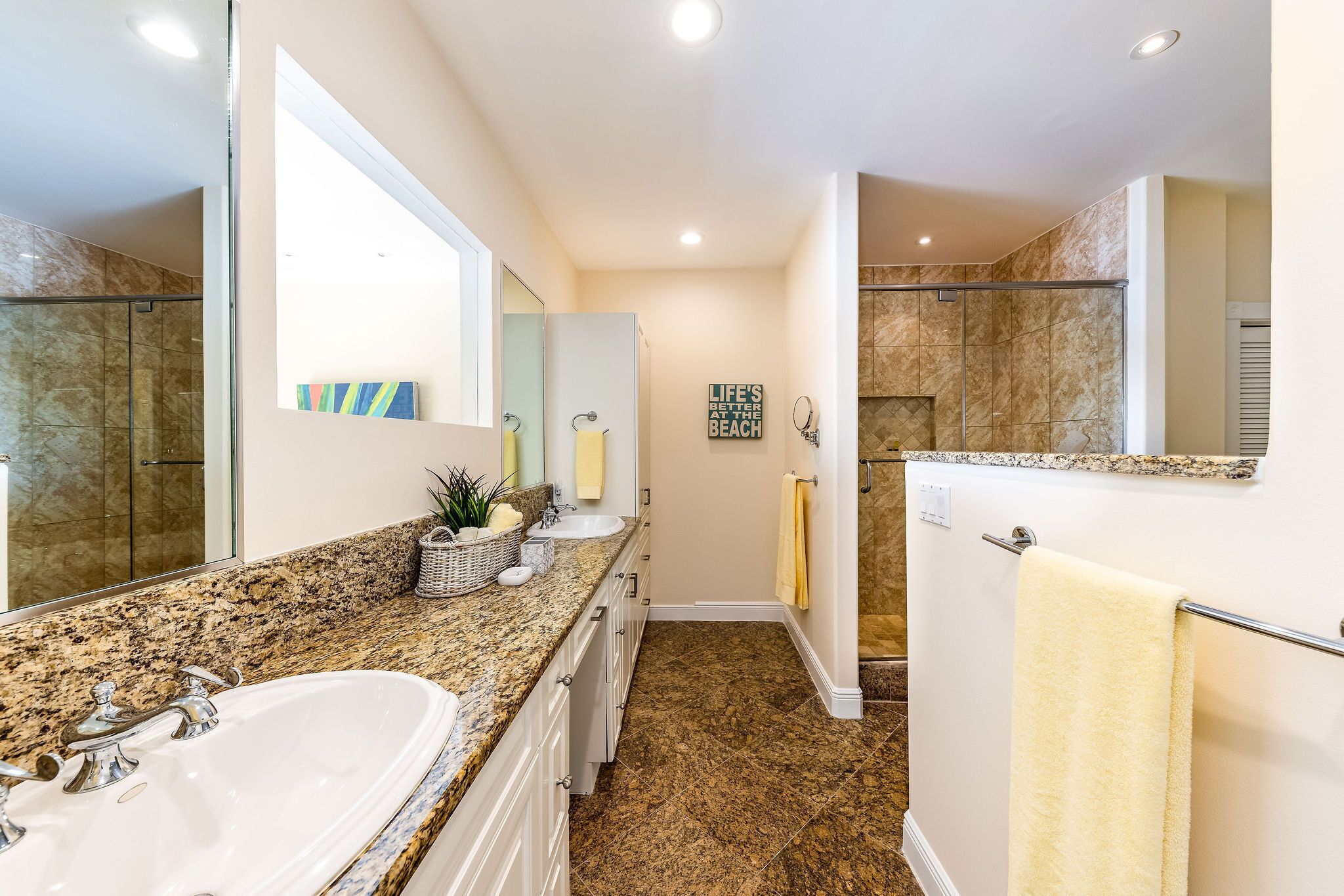 Un bagno moderno con un piano in granito, uno specchio grande, una doccia con porta in vetro e un porta asciugamani.