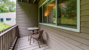 Une véranda abritée avec une table et des chaises, une fenêtre et une vue sur une maison et des arbres.