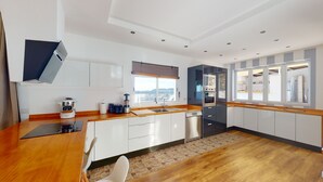 Een moderne keuken met een houten aanrecht, witte kastjes, een ingebouwde oven en een groot raam.