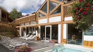 Un bâtiment moderne doté d’une piscine, de chaises longues et de jardinières suspendues.