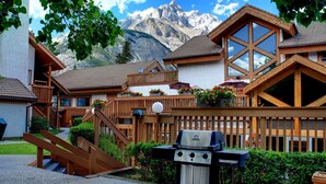 Un chalet doté d’une terrasse en bois, d’un barbecue et offrant une vue sur la montagne.
